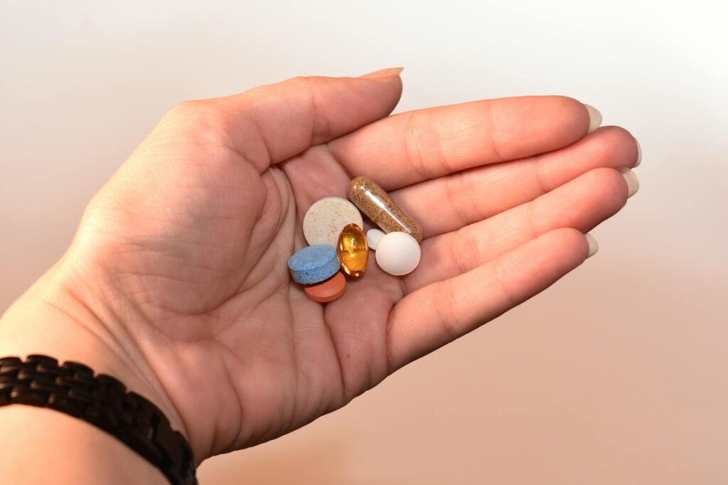 person holding medication pill and capsules